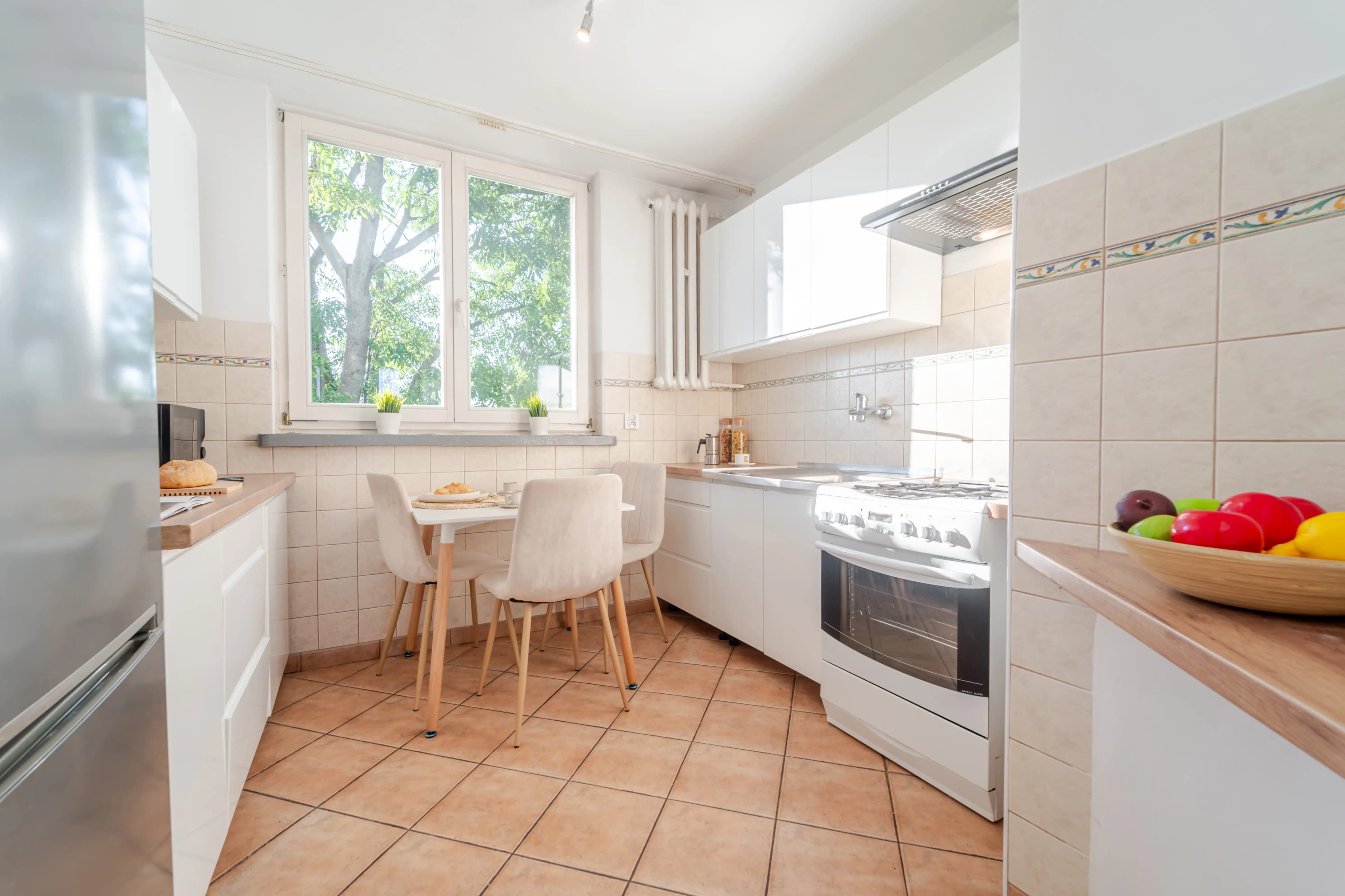 Tradycyjna kuchnia z miejscem na stół jadalnianym, białą kuchenką wolnostojącą.