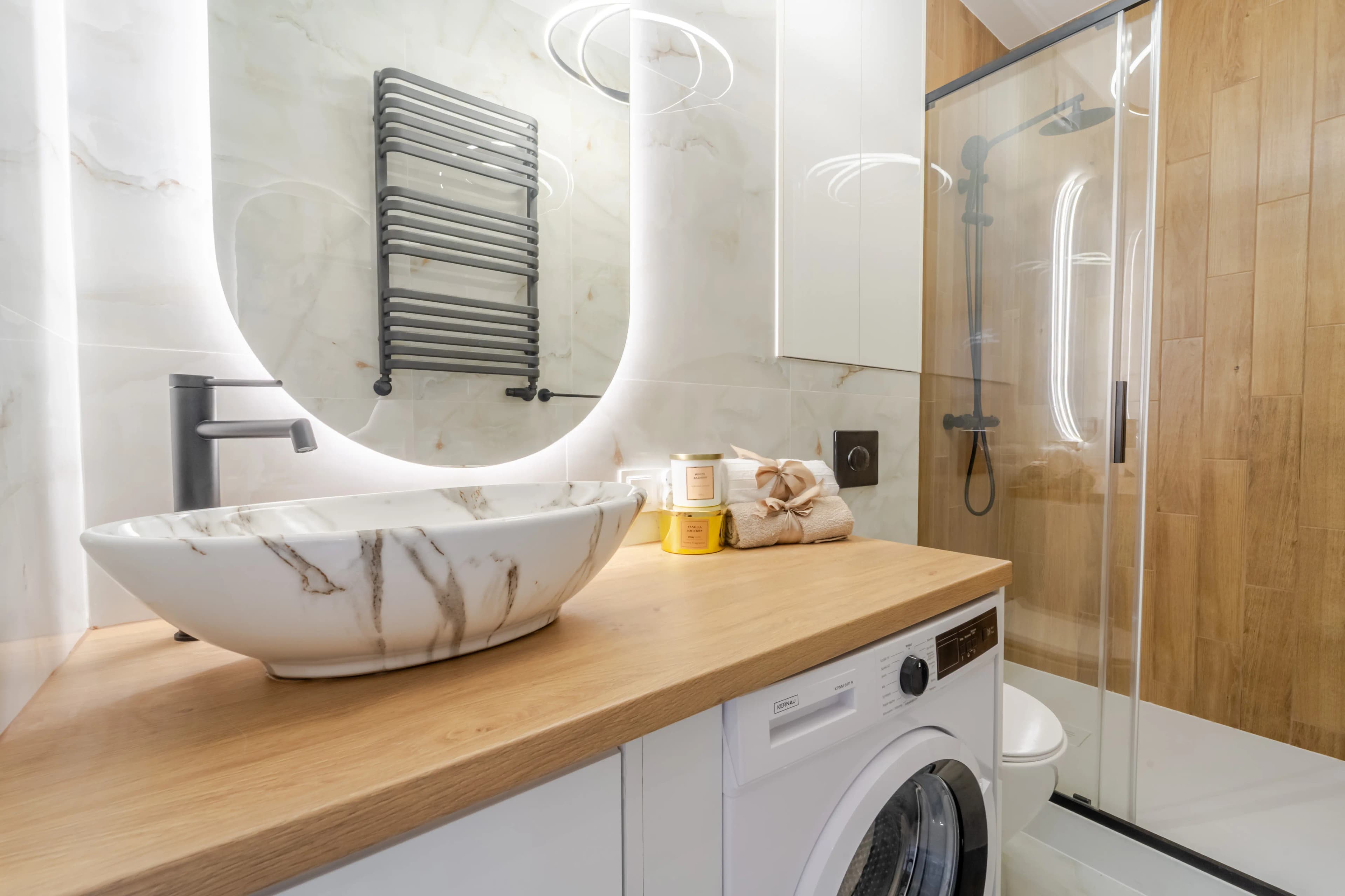 Stylowa łazienka z marmurową umywalką nablatową, drewnianym blatem i prysznicem typu walk-in.