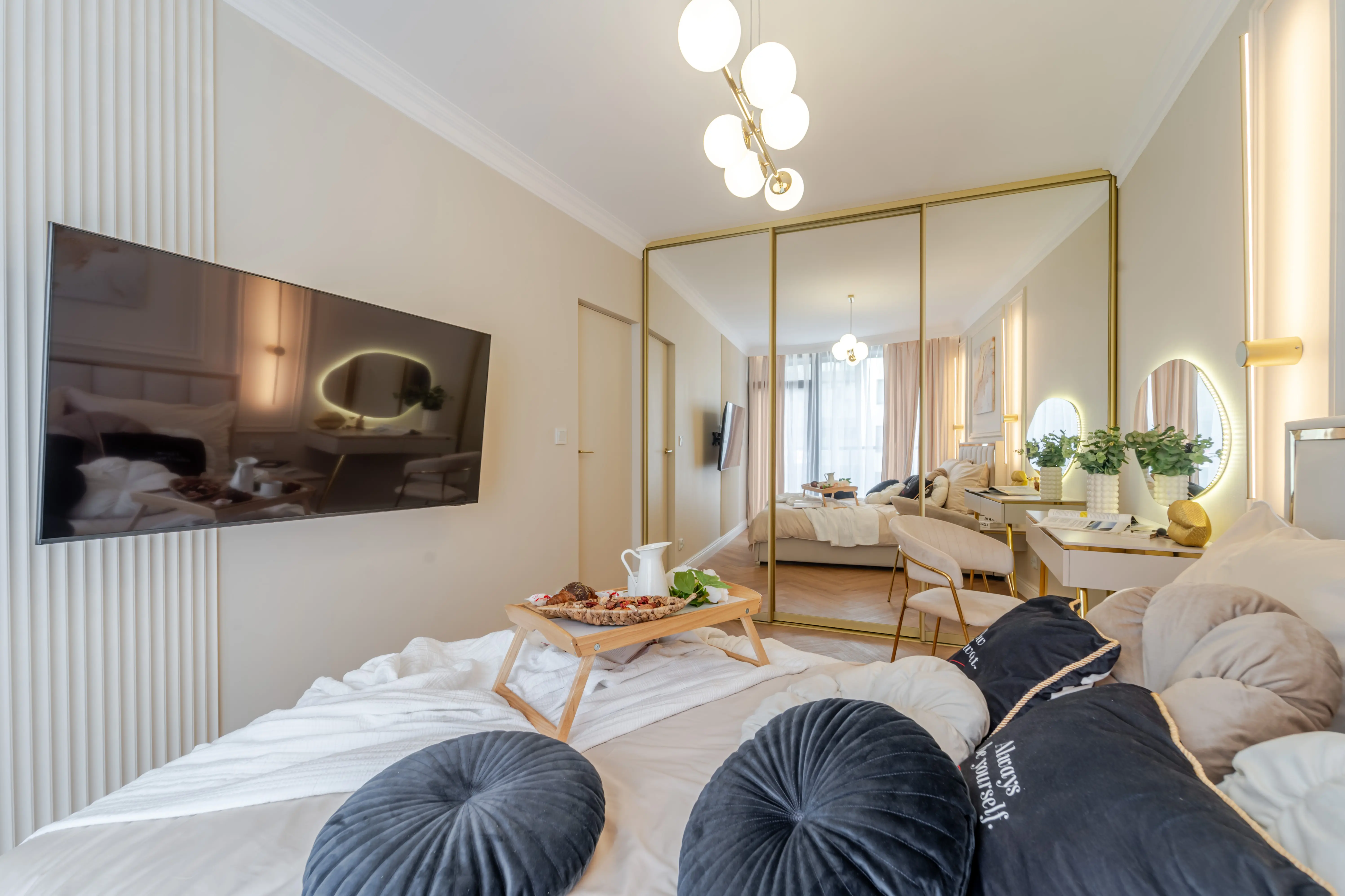 Duy pokój z sypialnią i telewizorem i szarą kanapą.