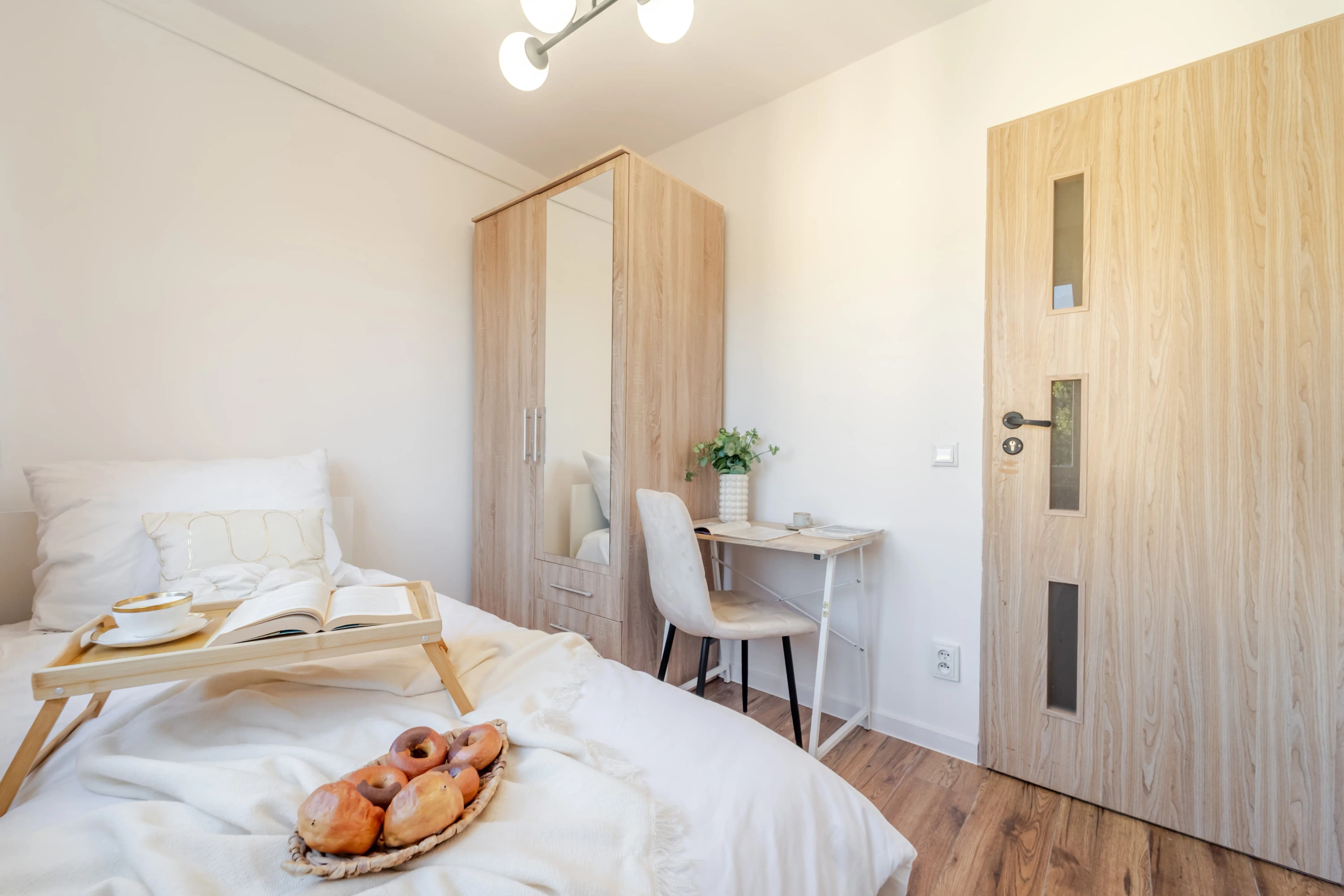 Nowoczesna, jasna kuchnia połączona z salonem, urządzona w beżach i drewnie.