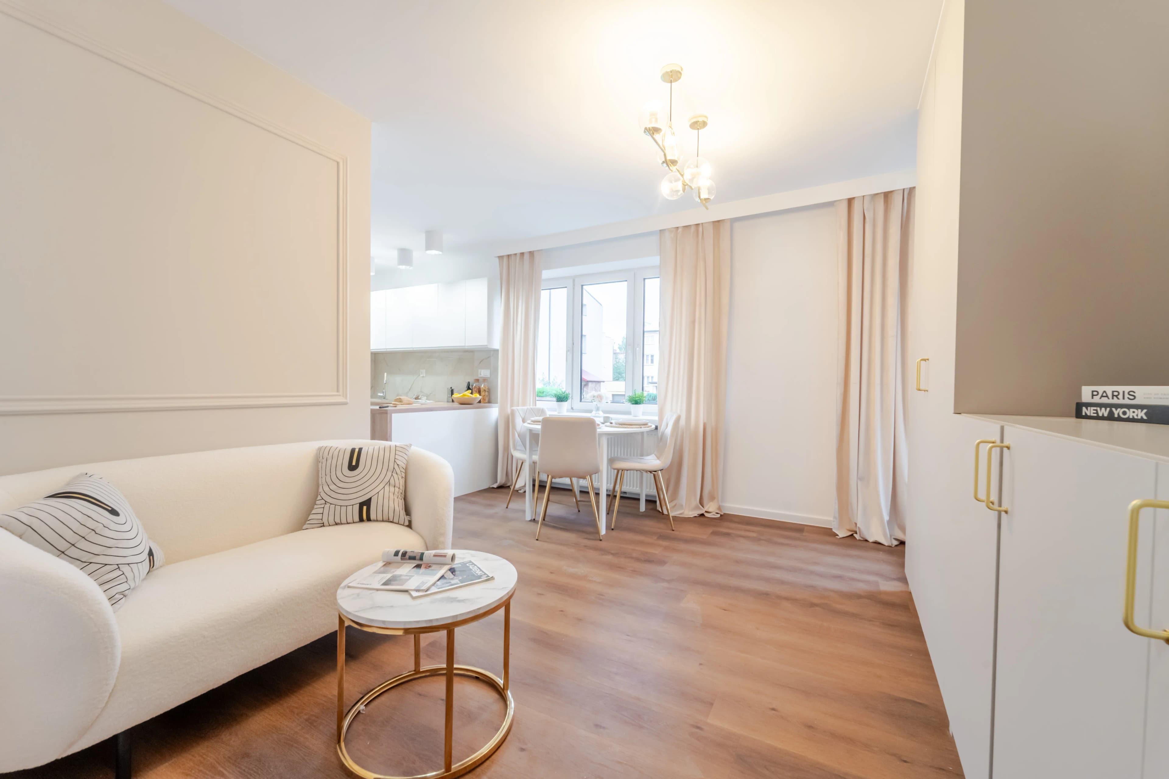 Profesjonalna fotografia jasnej, funkcjonalnej sypialni z drewnianą szafą, biurkiem i drzwiami w naturalnym odcieniu drewna.