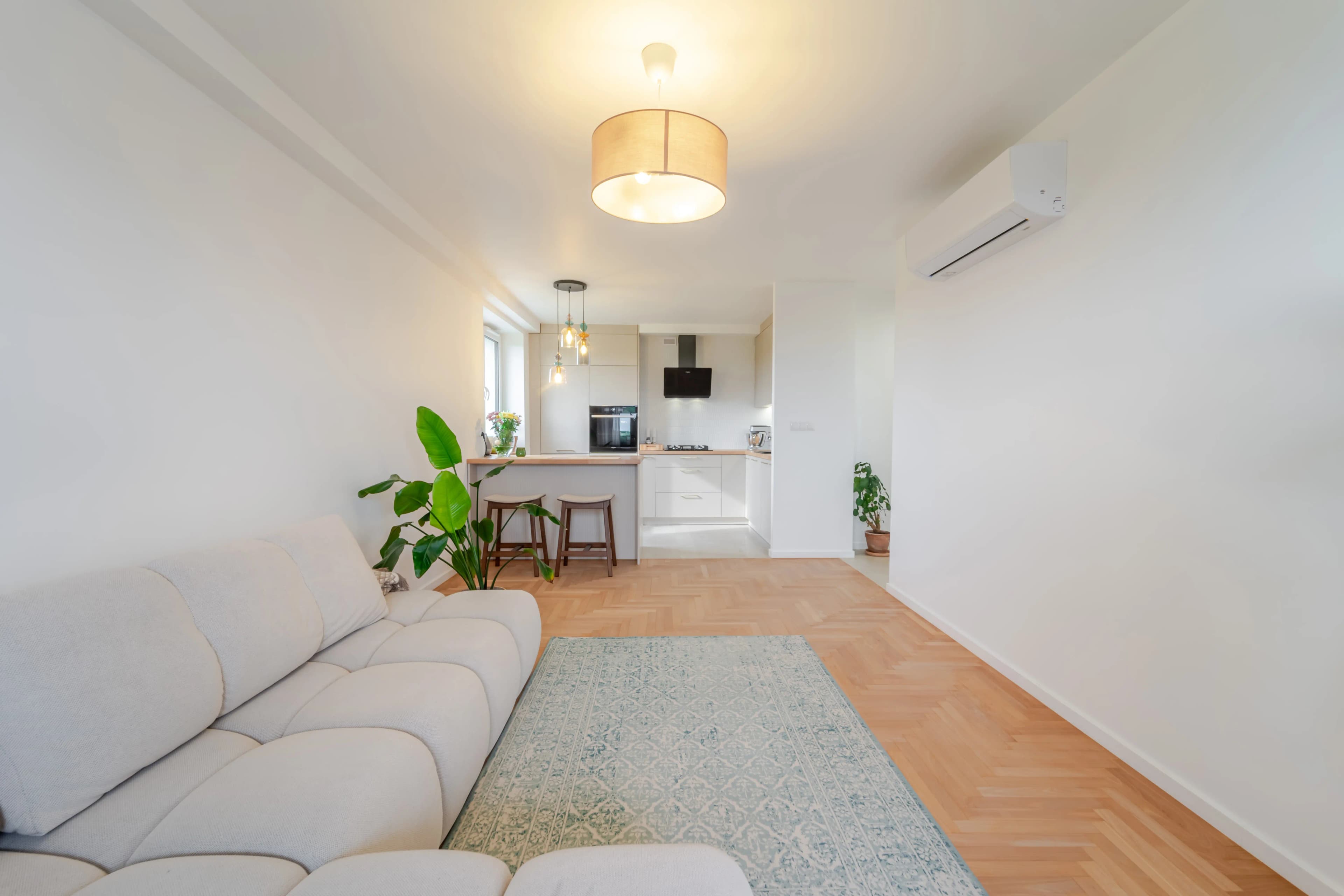 Zdjęcie wnętrza ukazujące nowoczesną, białą kuchnię w zabudowie korytarzowej z lakierowanymi frontami i drewnianymi akcentami.