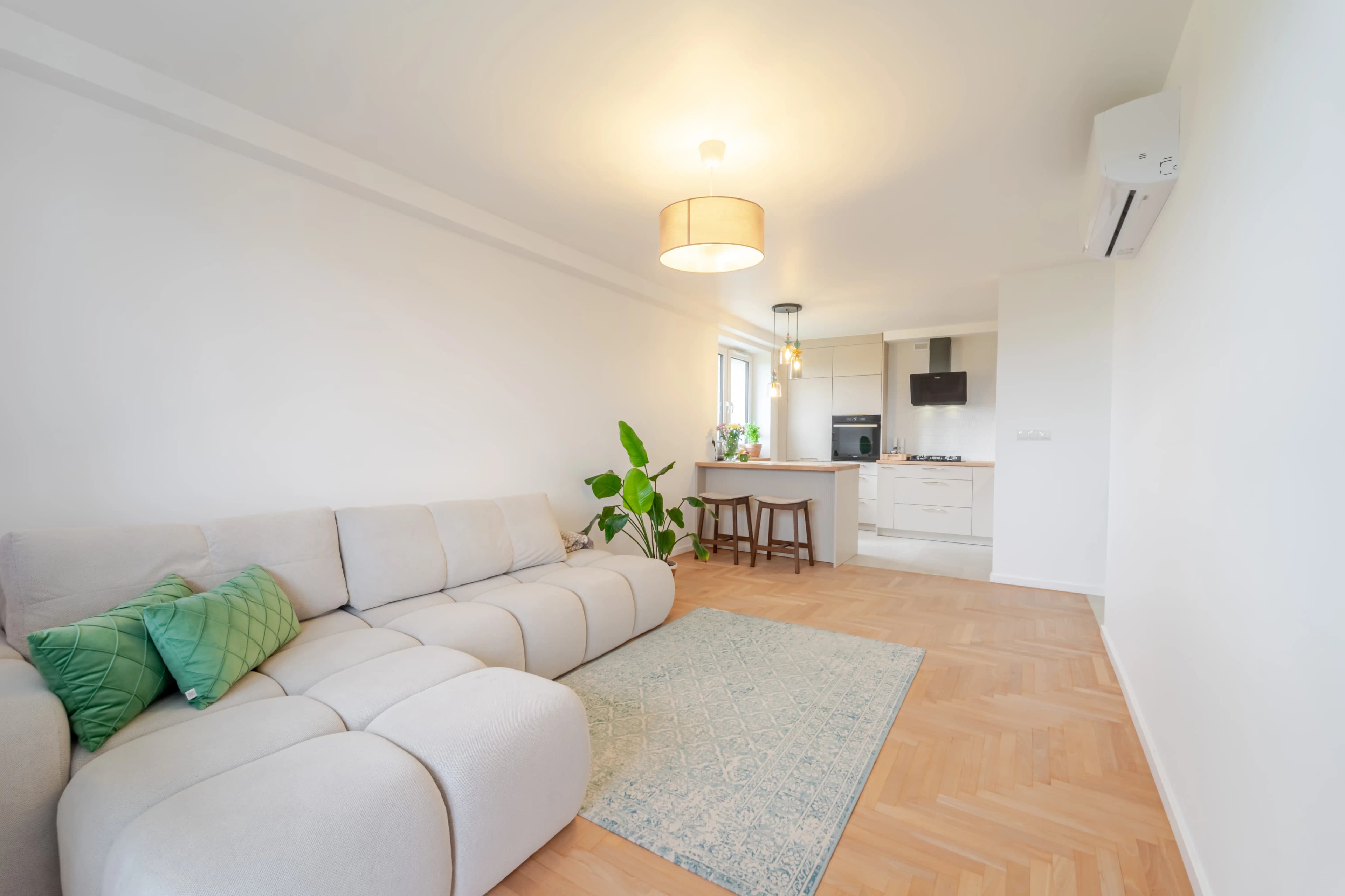 Profesjonalne ujęcie nowoczesnej sypialni z dużymi żaluzjami, szarym tapicerowanym łóżkiem i szafą z lustrzanym frontem powiększającą przestrzeń.