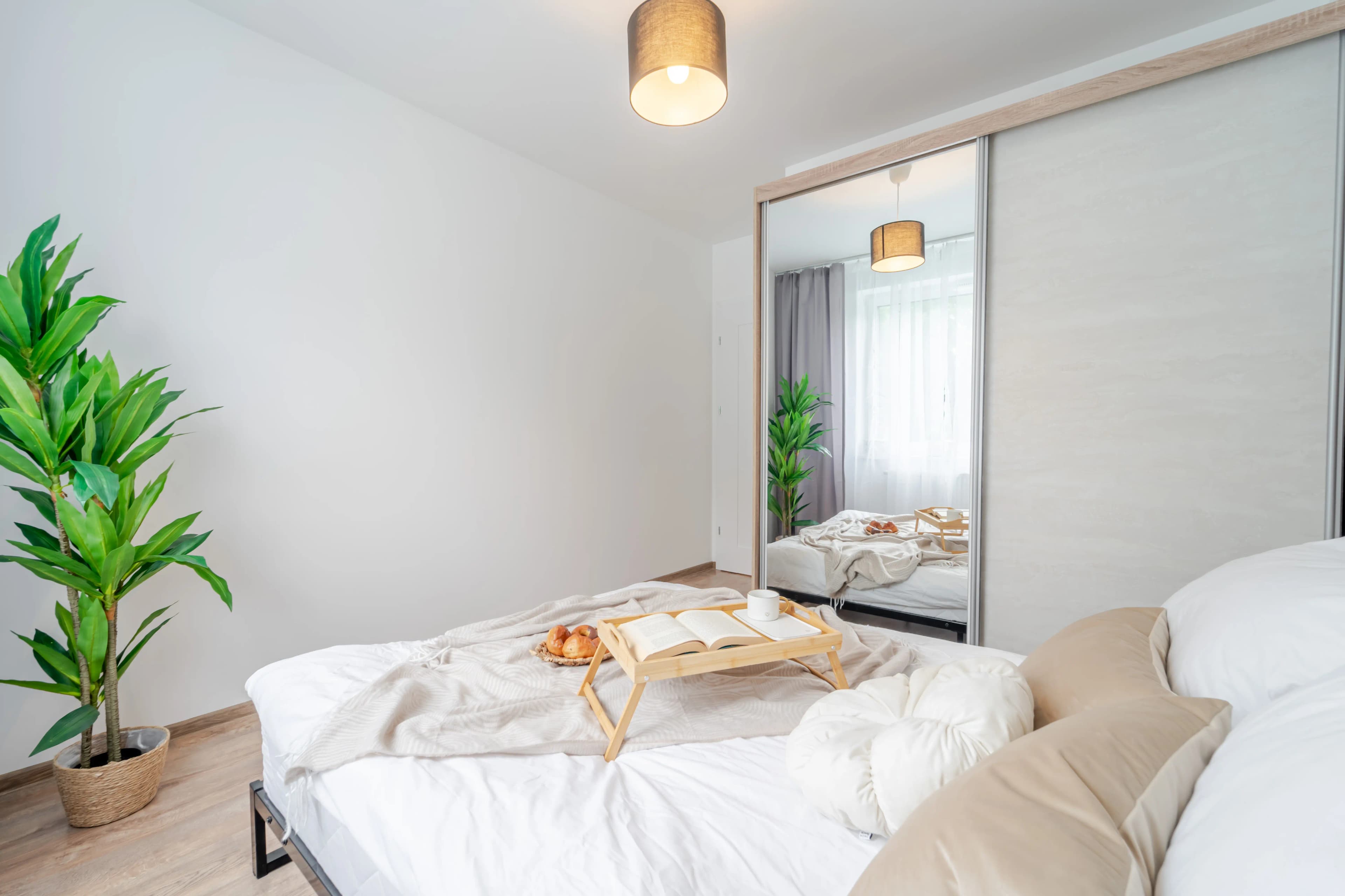 Widok na przestronną strefę wypoczynkową z dużą, jasną narożną sofą, szklanym stolikiem i ścianą telewizyjną w industrialnym stylu.