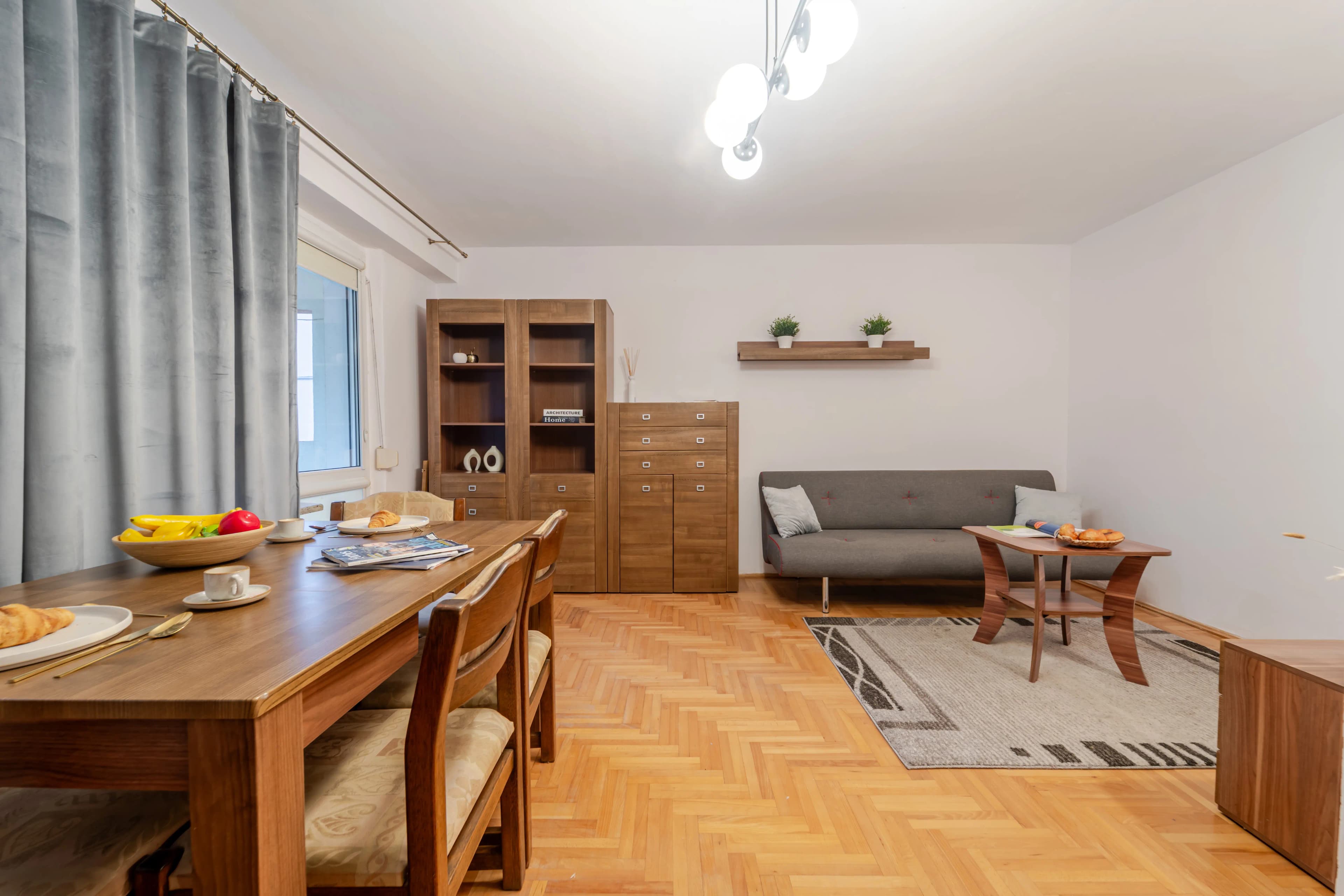 Aranżacja strefy jadalnianej w kuchni z drewnianym stołem, wygodnymi krzesłami i elegancką zastawą śniadaniową.