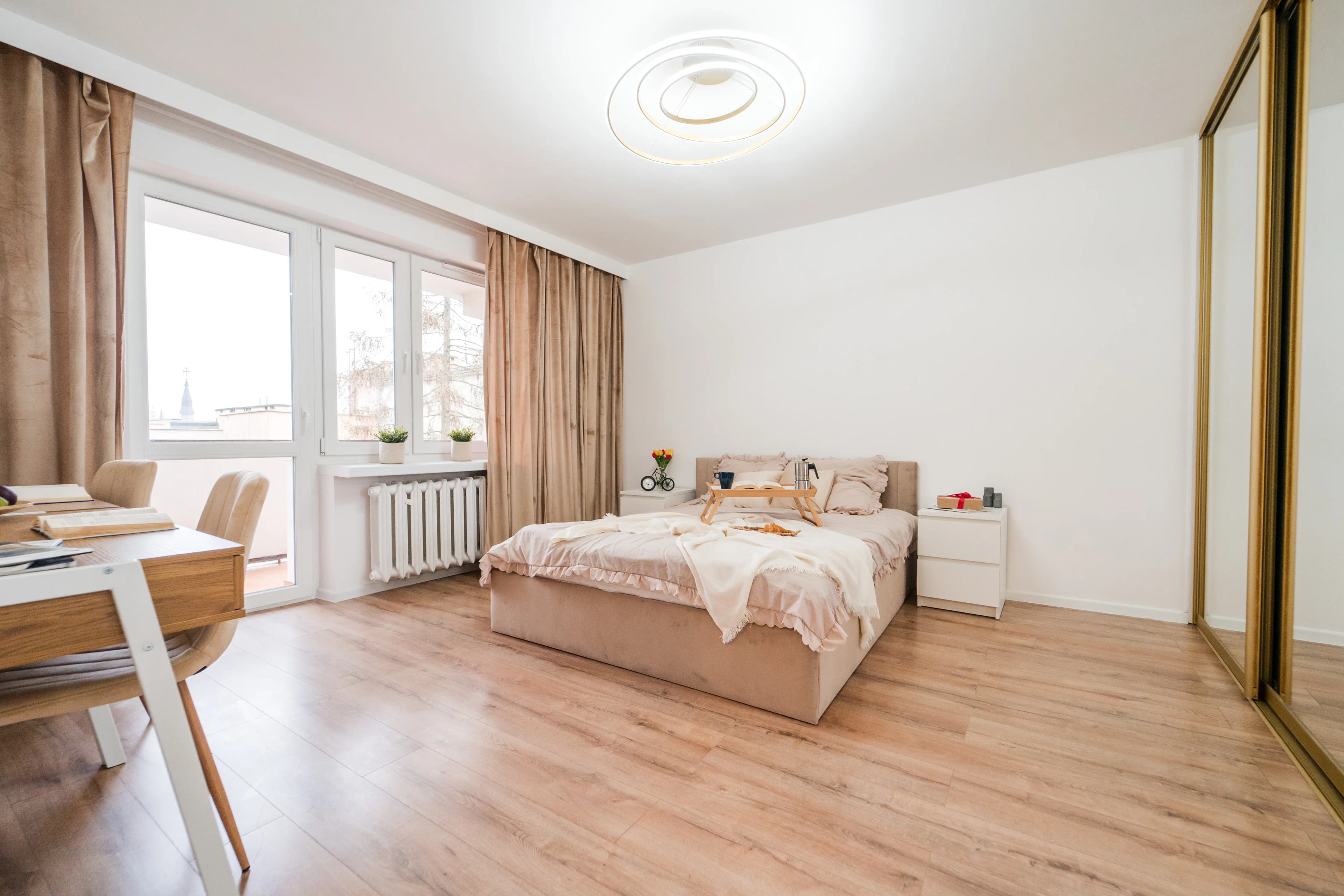 Kameralny pokój jednoosobowy z drewnianym łóżkiem, biurkiem do pracy i klasycznym parkietem na podłodze.